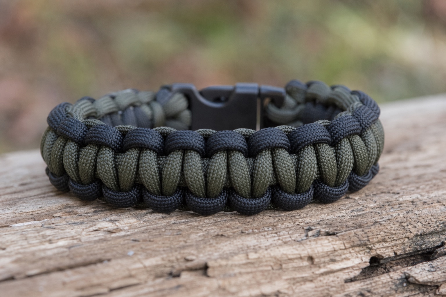 Finished cobra weave paracord bracelet photographed from the side on rustic wood, natural light